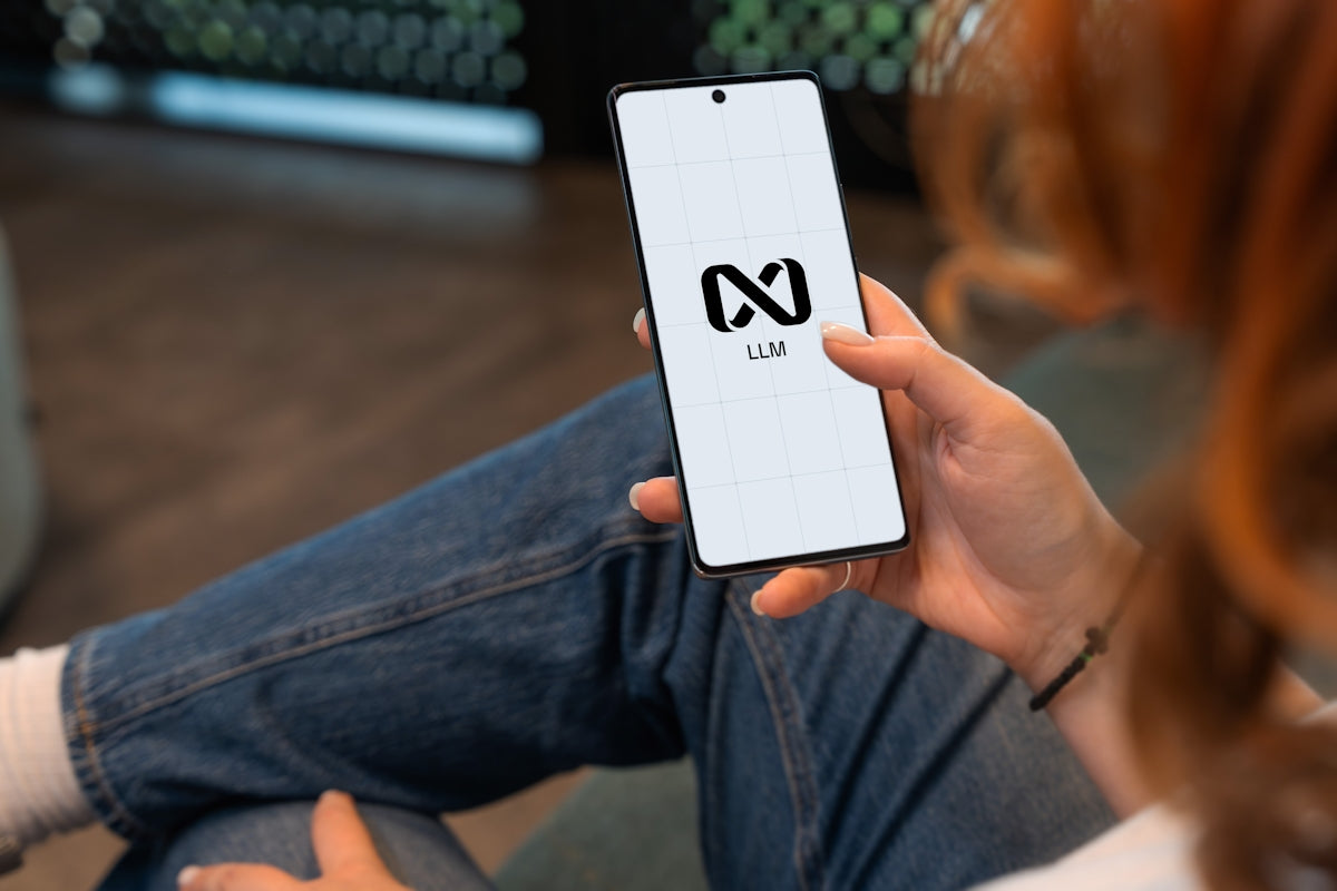 Person holding a smartphone with a logo on screen.